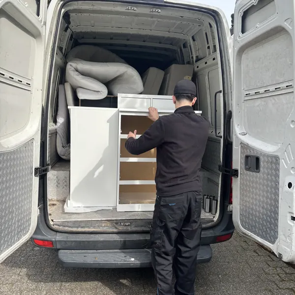 Mitarbeiter verlädt einen Schrank in den Transporter